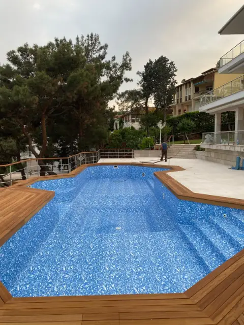 Ahşap deck ile çevrili, mozaik desenli kaplamalı yüzme havuzu